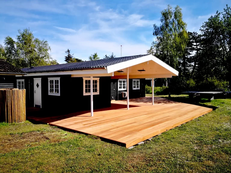 Terrasse i hårdttræ og hårdttræ strøer. Træsort er guariuba. Terrasse startede med at være meget gul, i løbet af få uger blev den mere brun, efter flere uger var den meget brun og efter et halvt år blev den sølvgrå. Sommerhuset er beliggende i Saksild