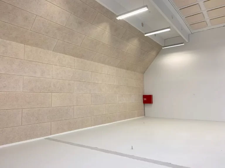 Her er lavet en stor skillevæg i en lagerhal. Der er fermacell gips på den ene side. Den anden er der Troldtekt plader på.
